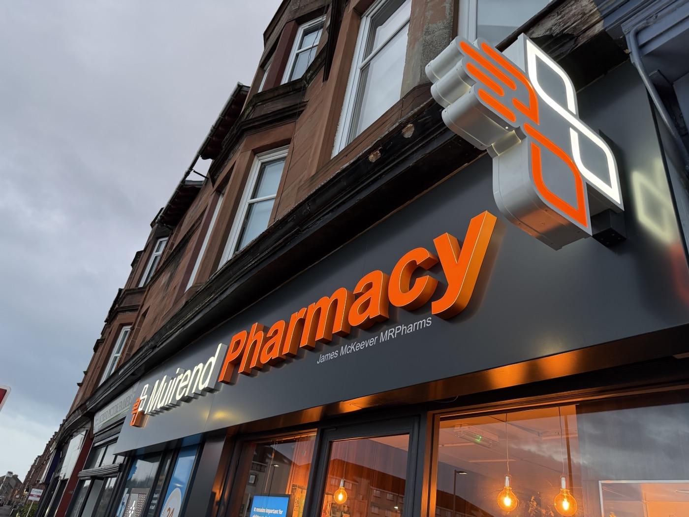 Muirend Pharmacy illuminated fascia sign on Clarkston Road, Glasgow Southside